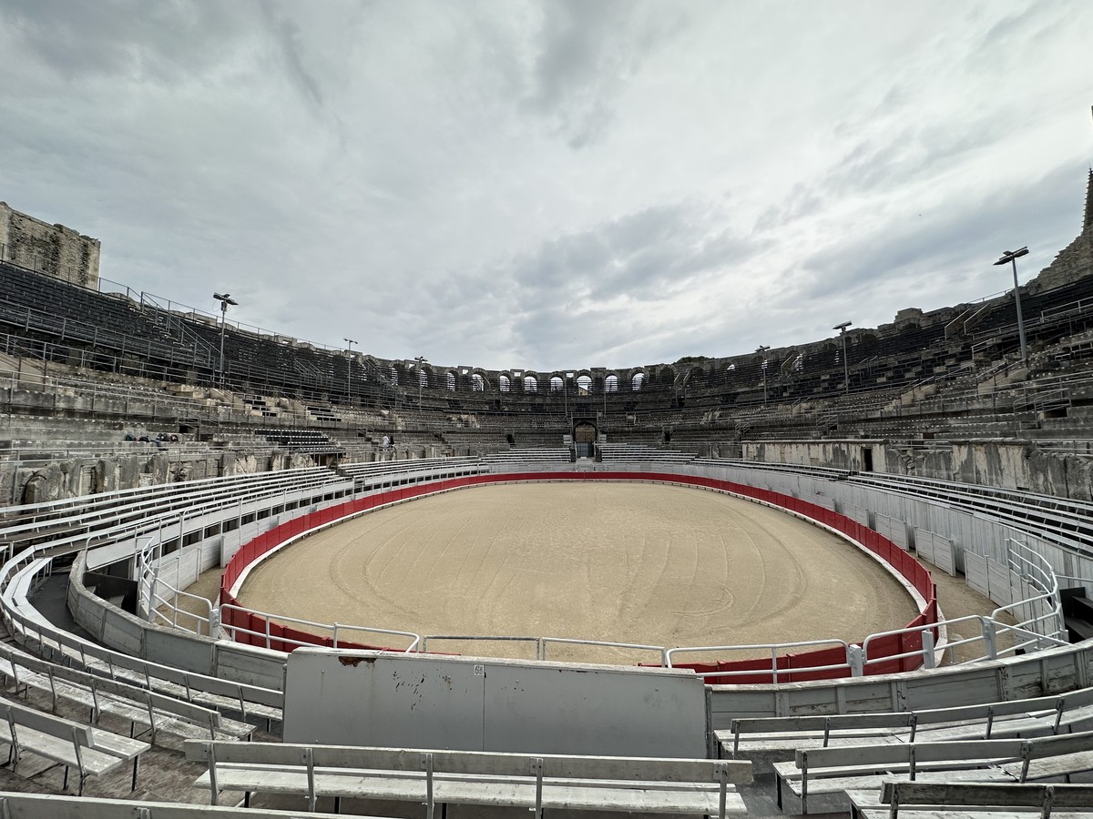 View from inside the Arles Amphitheater looking across the sandy arena floor with stone seating tiers rising above