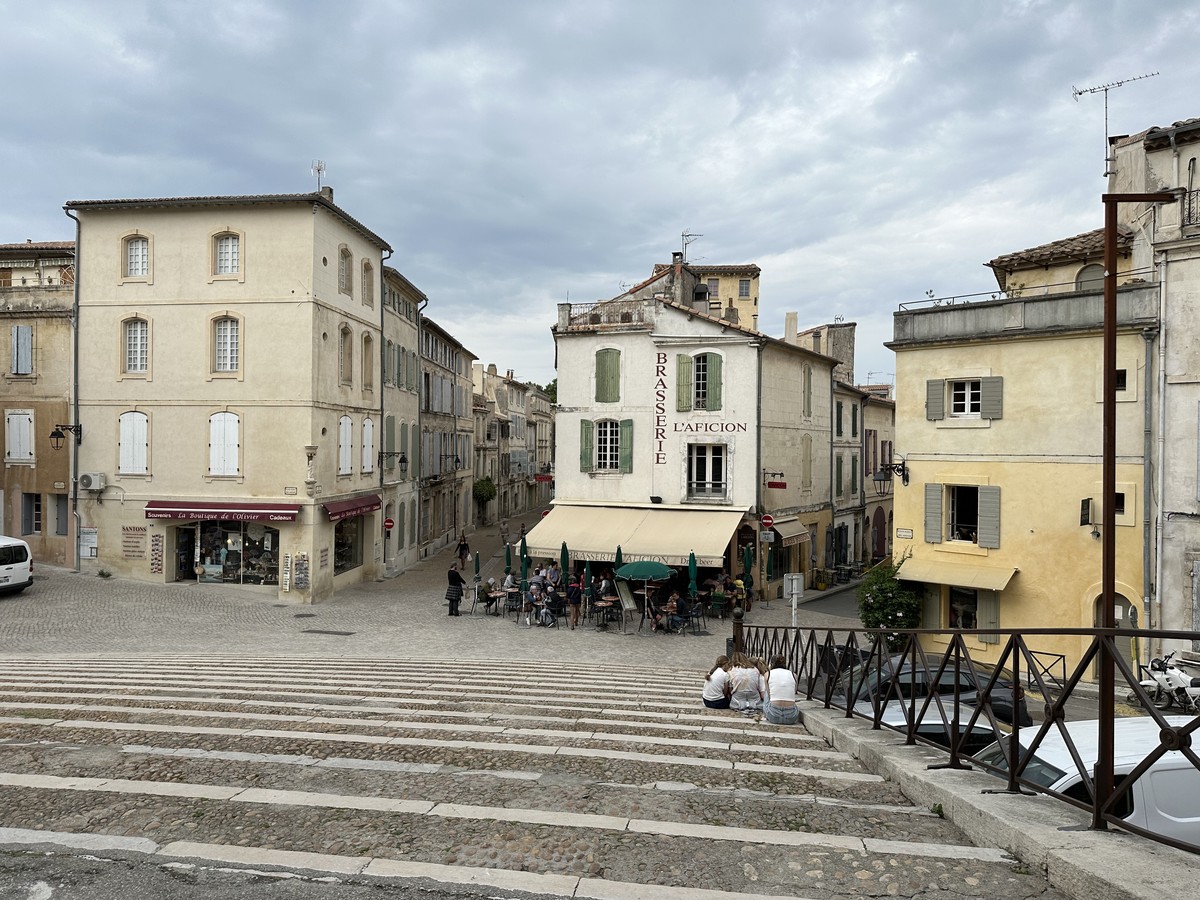 Place de l’Amphithéâtre in Arles with café tables and buildings built into the curved exterior of the Roman amphitheater