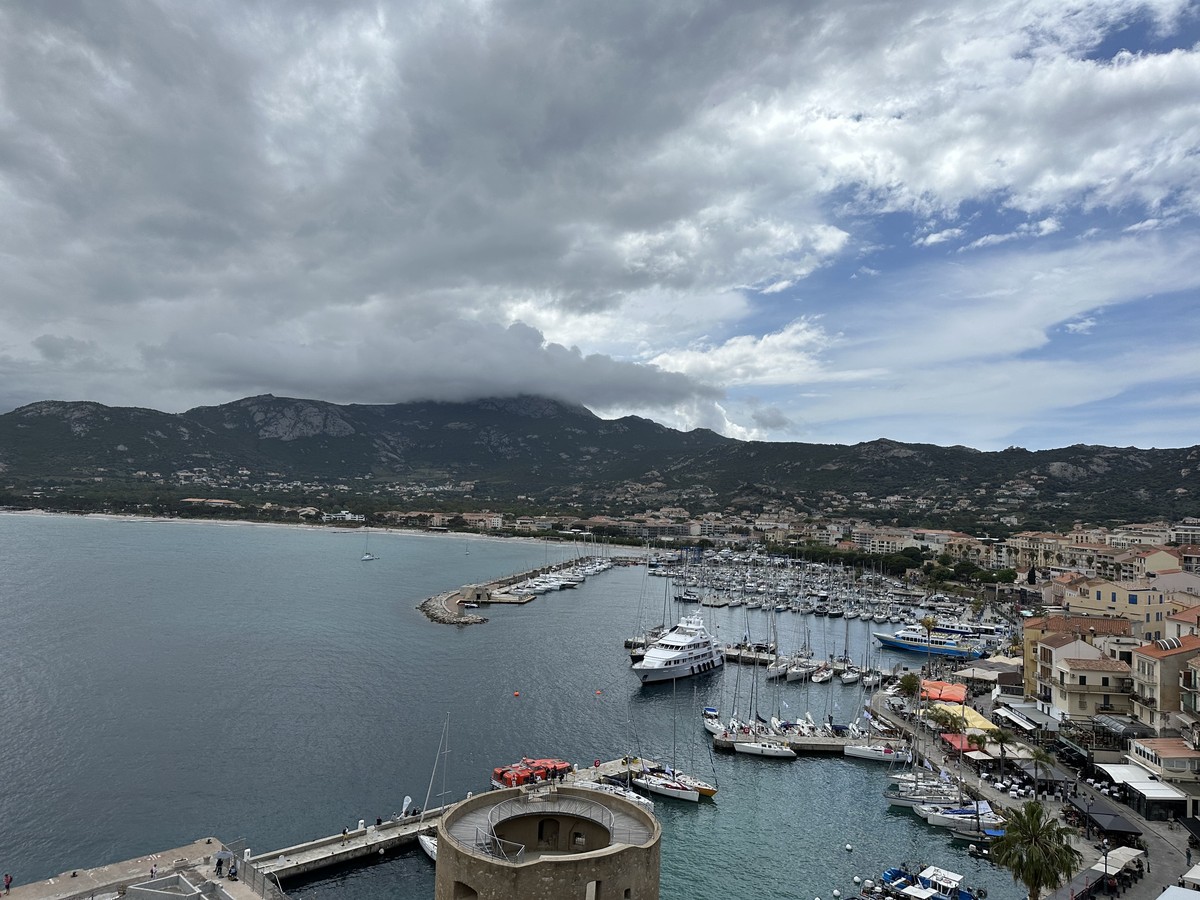 Corsican marina with colorful buildings and boats in clear blue water
