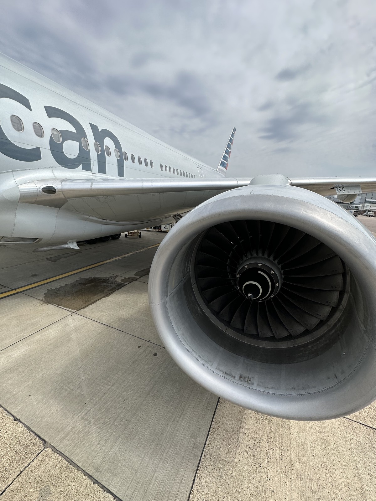 American Airlines jet engine on the tarmac at Heathrow Airport under dramatic clouds