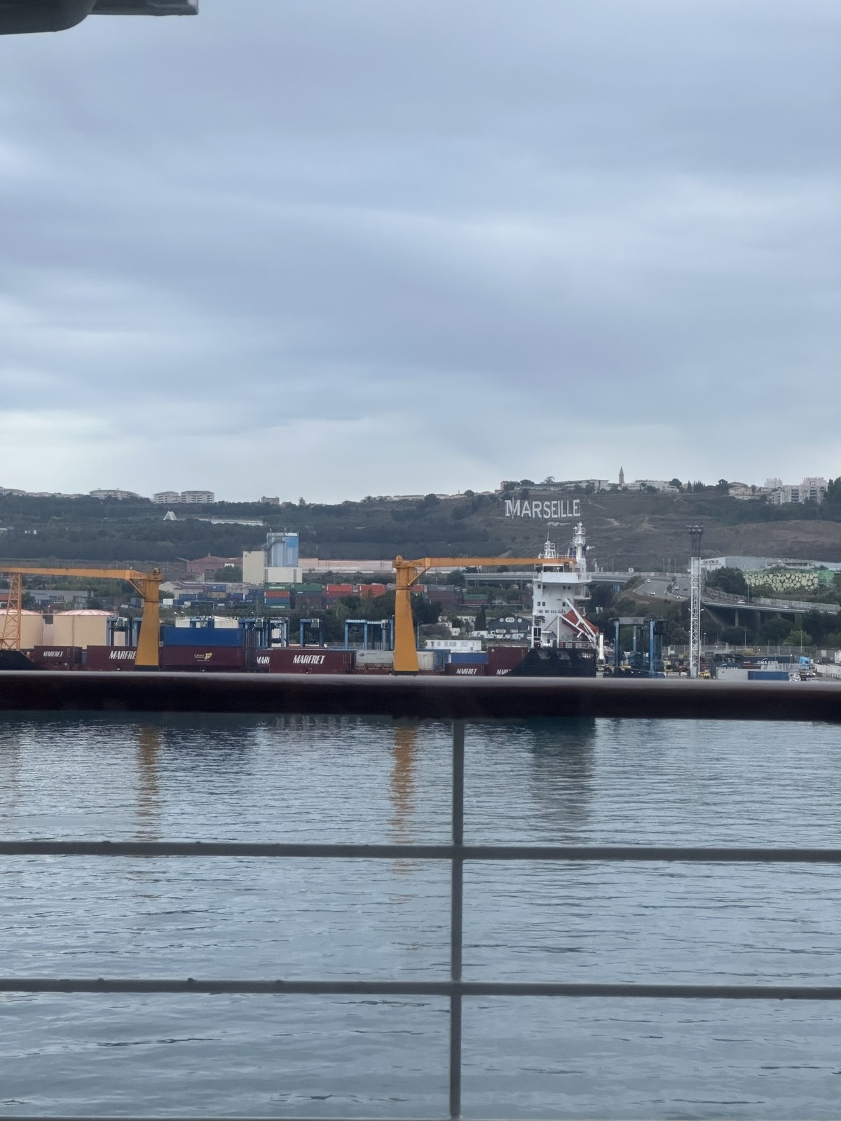 View from the cruise ship showing the MARSEILLE sign on the hillside above the port with yellow cranes