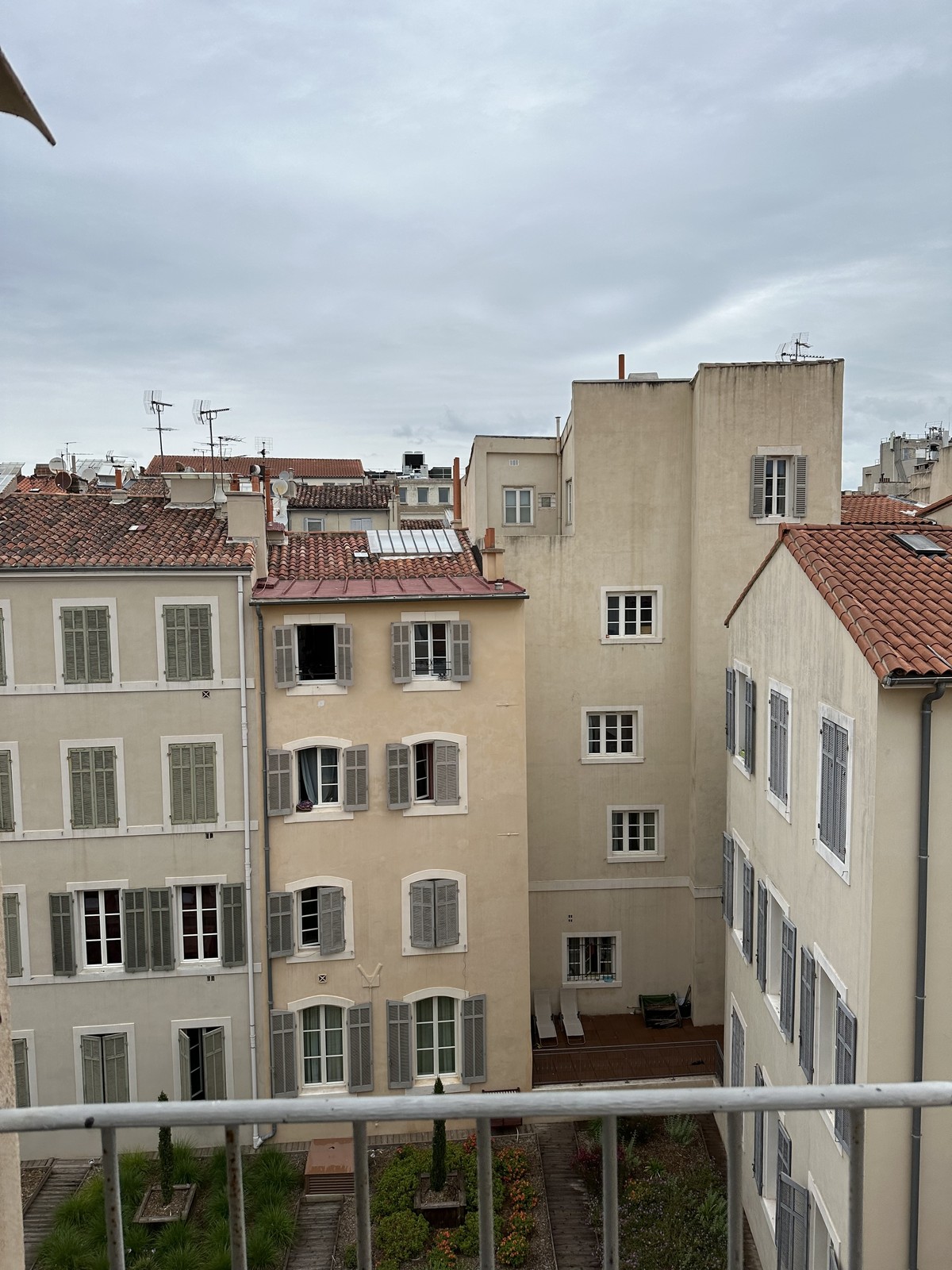 View over Marseille rooftops from an upper floor showing pastel buildings and terracotta tiles