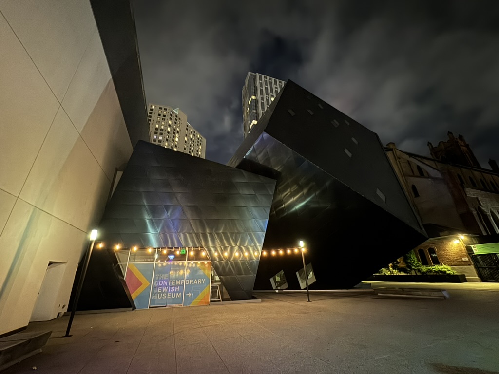 The Contemporary Jewish Museum at night, angular modern architecture lit up against the San Francisco skyline