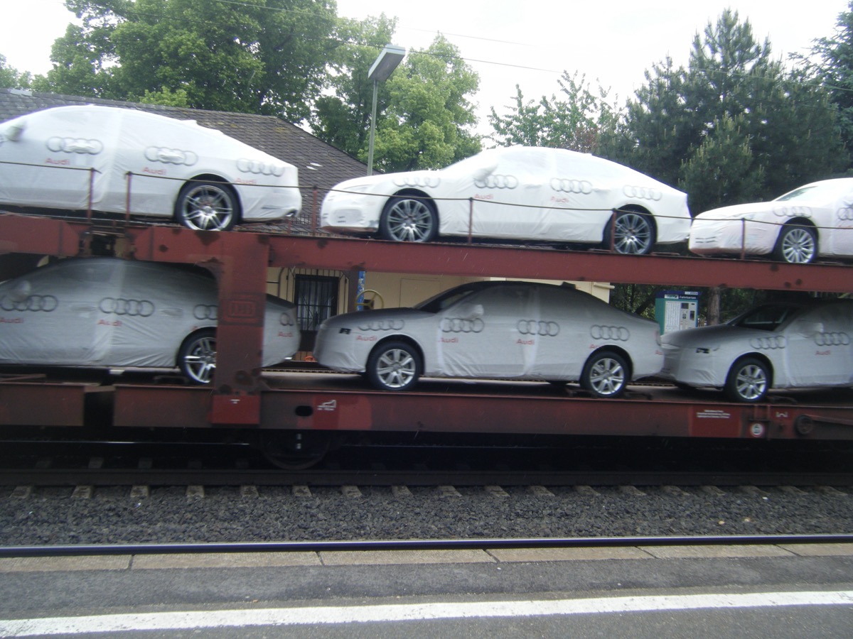 Brand new Audi cars wrapped in white covers being transported on a rail carrier in Germany