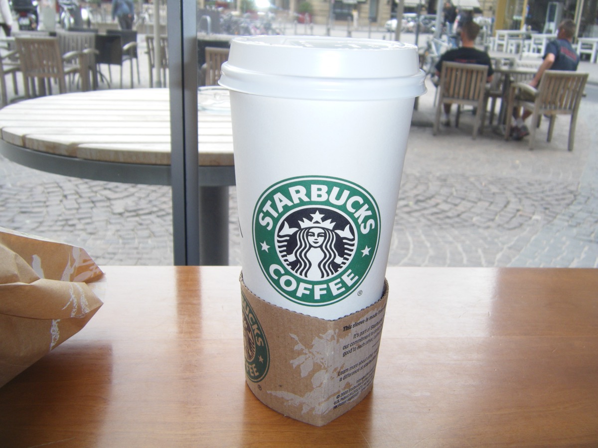 Starbucks coffee cup on a table with cobblestone Frankfurt plaza in background