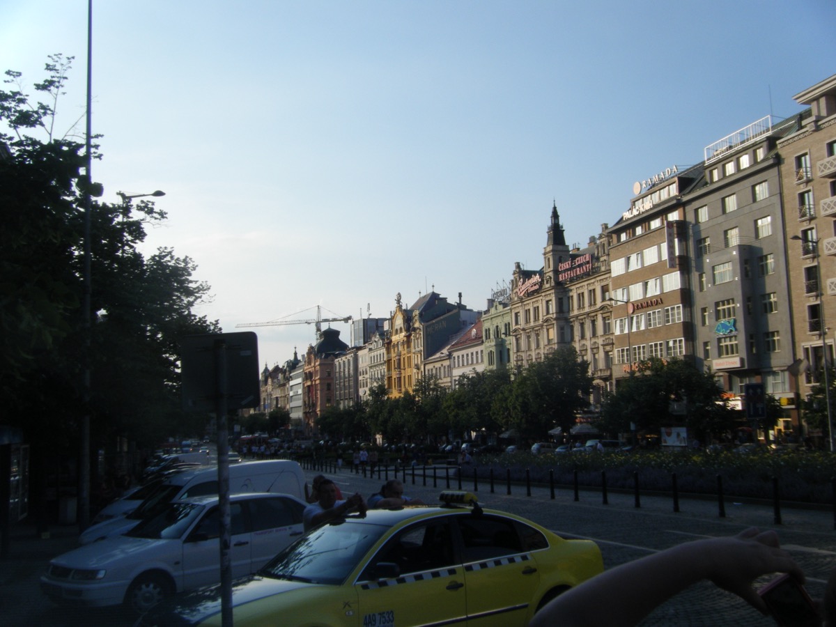 Wenceslas Square boulevard in Prague with ornate buildings and yellow taxi