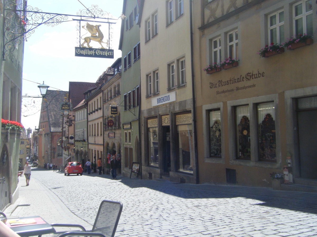 Cobblestone street in Rothenburg with Gasthof Greifen inn sign and traditional German shops