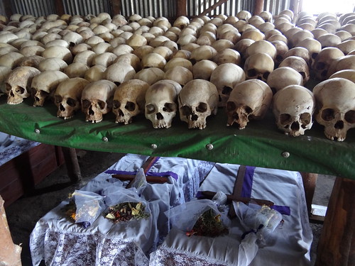 Rows of skulls arranged on shelves inside the Bisesero memorial with flower offerings placed in front