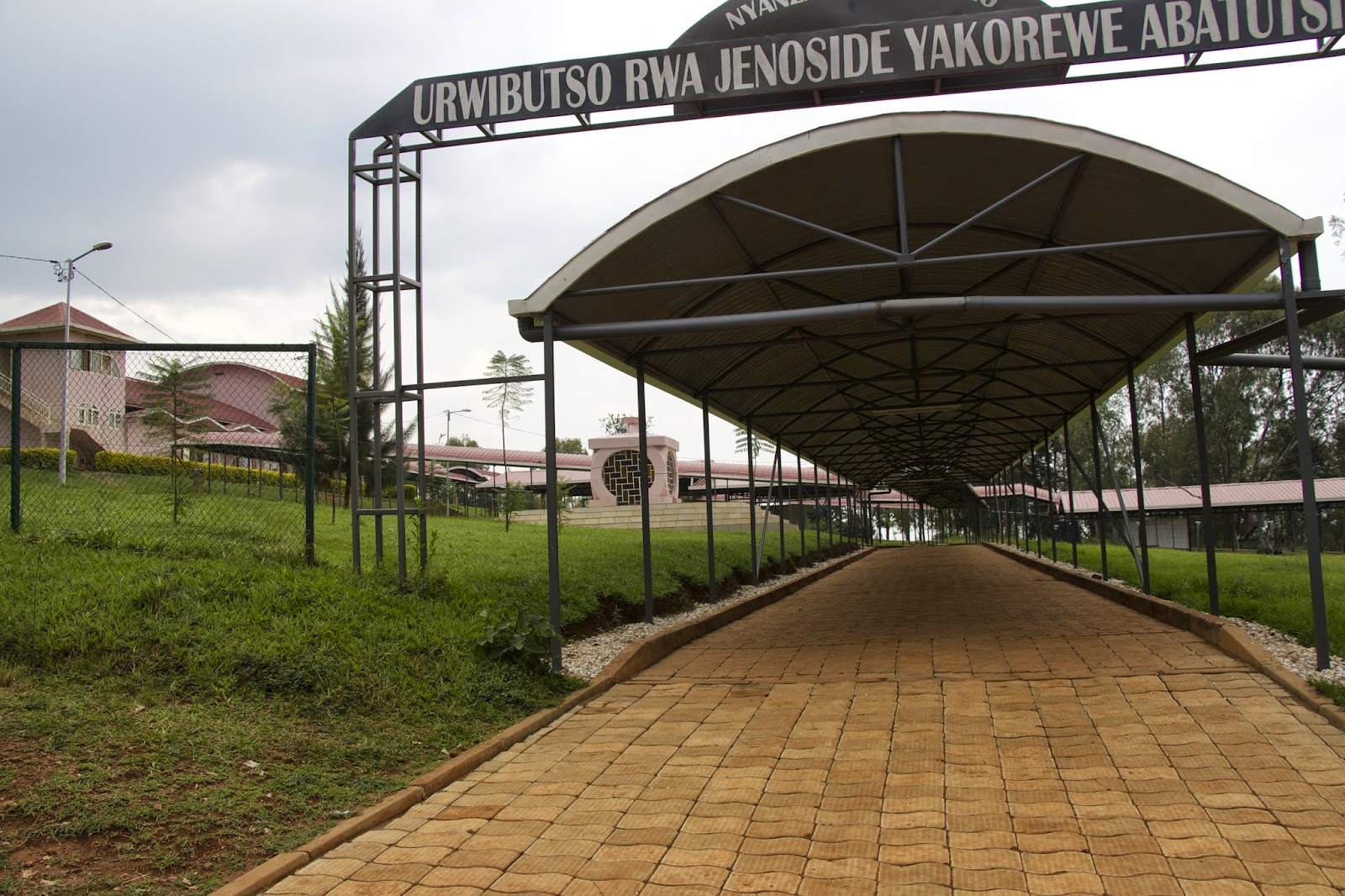 Covered brick walkway leading into the Nyanza-Kicukiro genocide memorial grounds