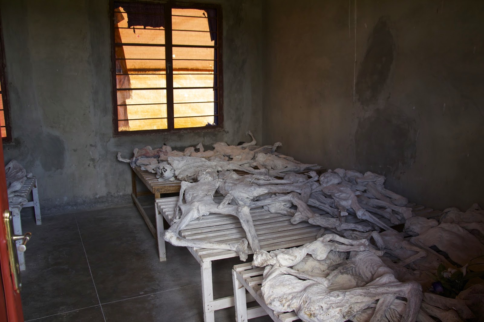 Lime-preserved remains of genocide victims laid out on wooden platforms in a room at the Murambi memorial
