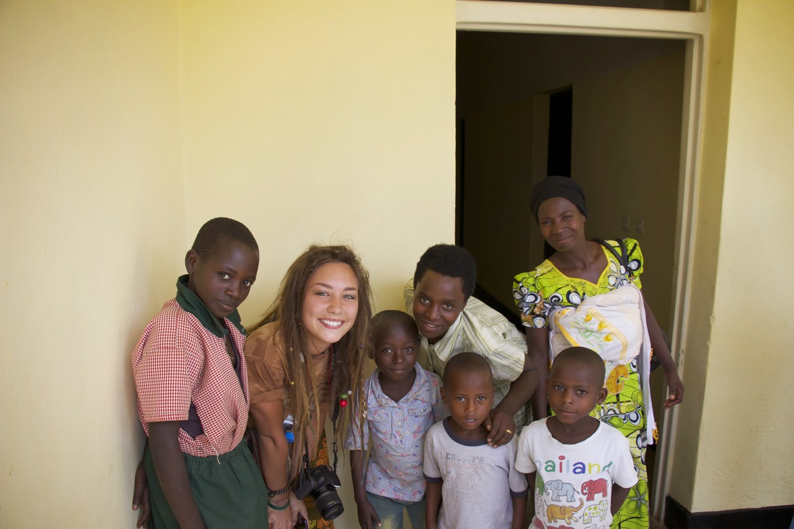 A traveler posing with local women and children at the Mayange Health Center