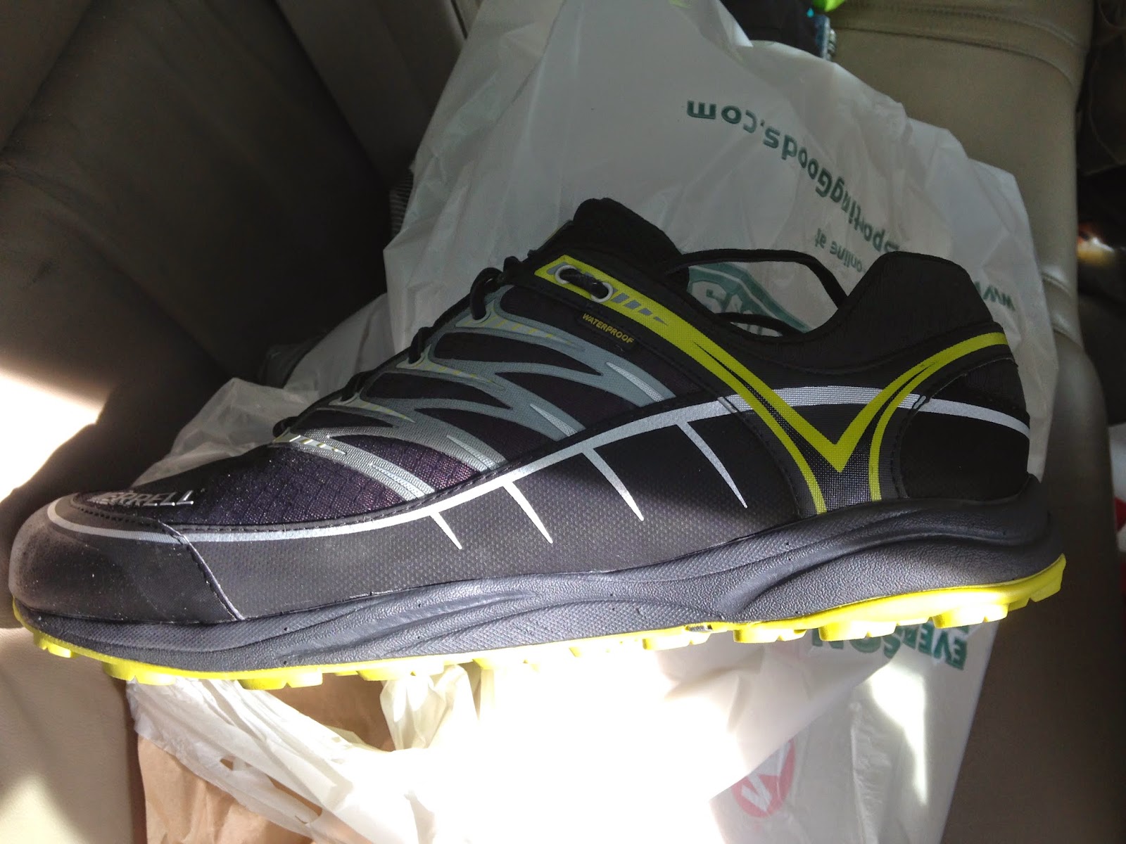 New waterproof hiking shoe on a car seat with a sporting goods store bag