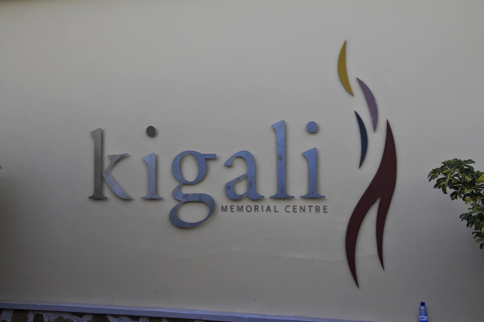 Kigali Memorial Centre sign on a wall with the memorial's flame logo