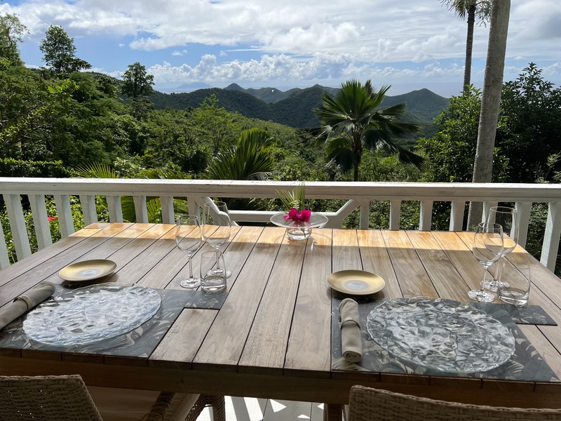 Table set for dinner on a veranda overlooking mountains at La Villa Hibiscus