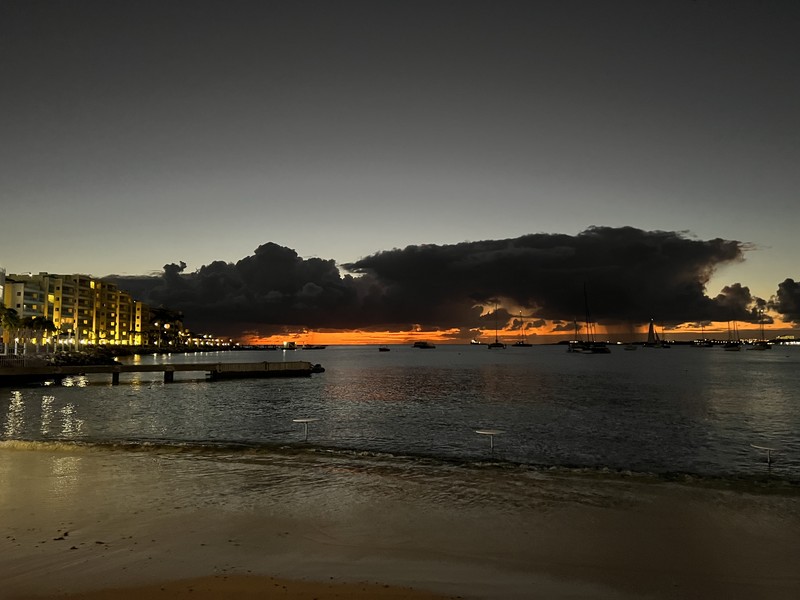 Dramatic sunset over Simpson Bay with storm clouds and boats