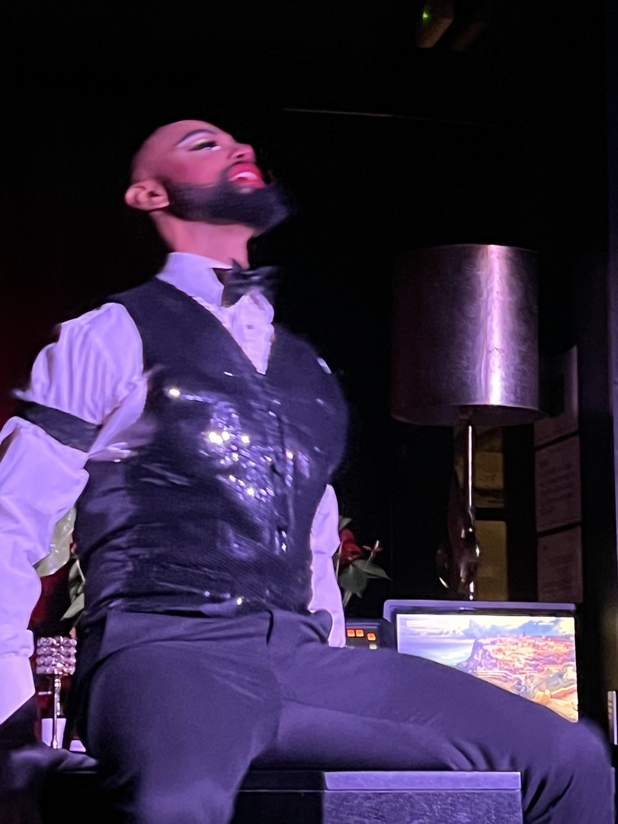 Drag performer on stage holding a red rose