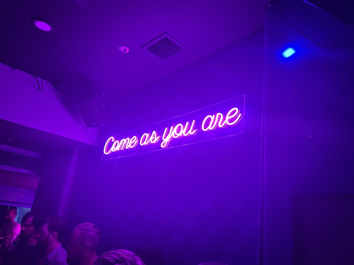 Neon Come As You Are sign in purple light at a Madrid bar