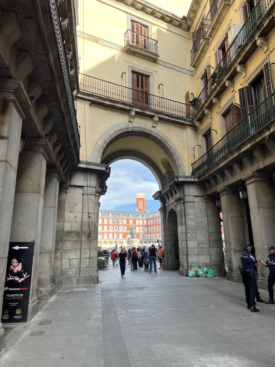 Stone archway entrance to Plaza Mayor framing a view of the square
