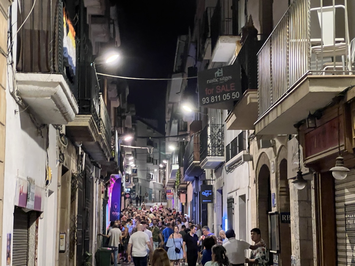 Sitges nightlife street with pride flags and crowds