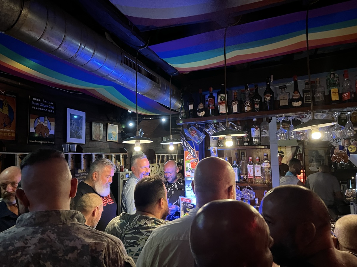 Crowded bar interior with rainbow-painted ceiling