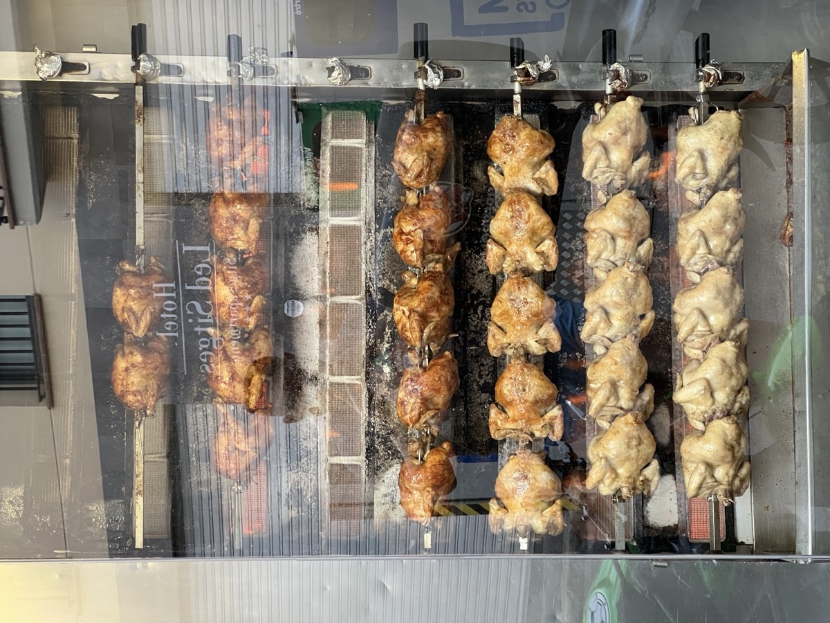 Rotisserie chickens spinning in a restaurant window