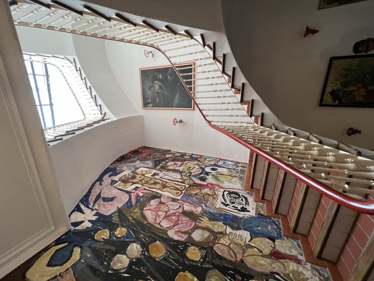 Curved staircase with colorful mural and paintings