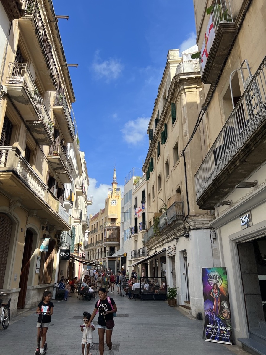 Narrow Sitges street with church tower visible in distance